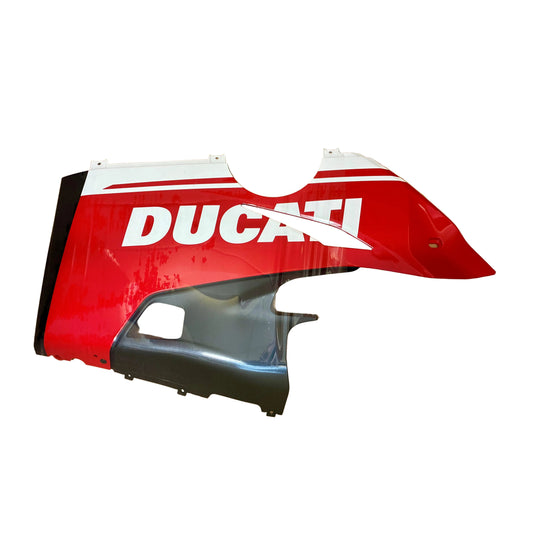 A red and white Ducati motorcycle fairing panel with the brand name 'DUCATI' in white, displayed inside a brown cardboard box alongside a black plastic component.
